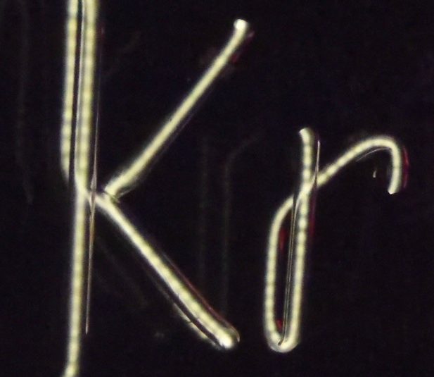 Rurka neonowa wypełniona kryptonem, uformowana w dwie litery "Kr". Gaz wewnątrz rurki świeci na biało