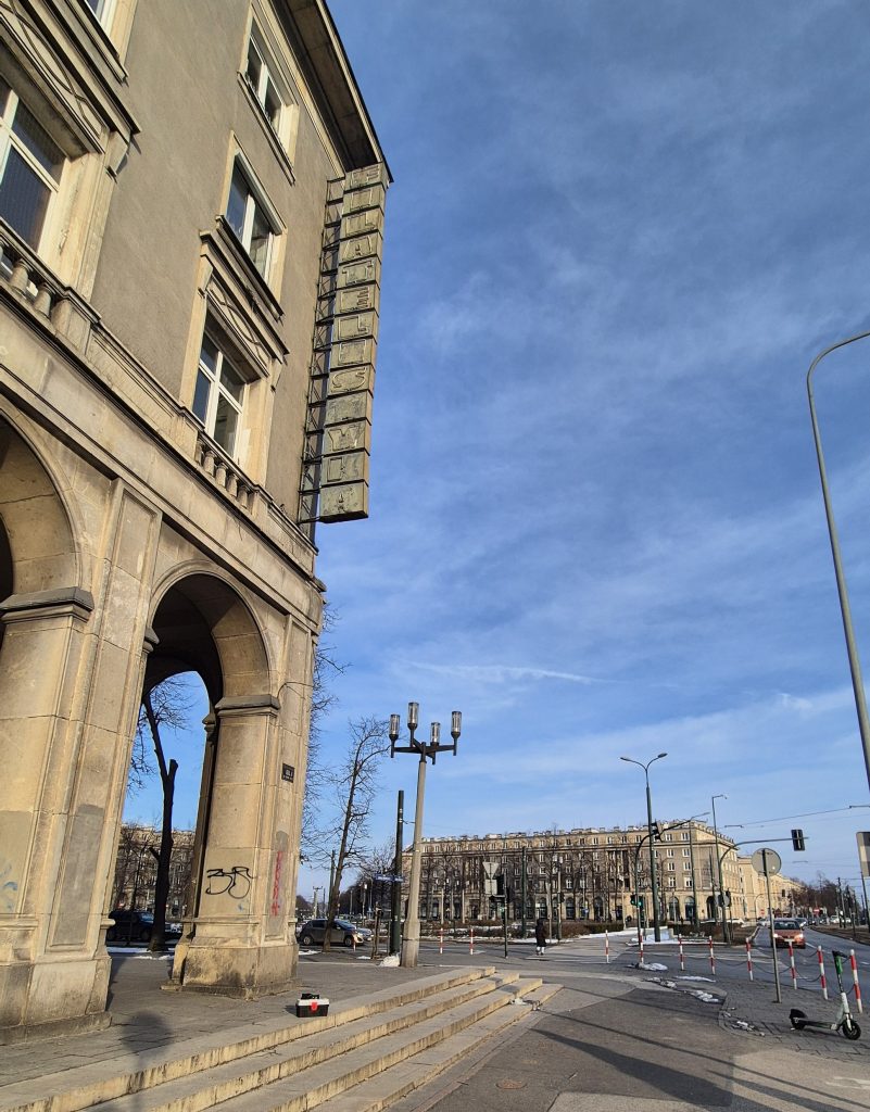 Zabytkowy neon Filatelistyka na kamienicy os. Centrum D 1 w Nowej Hucie (Kraków). Neon składa się z prostopadłościenych pudeł z literami układającymi się w pionowy napis FILATELISTYKA.