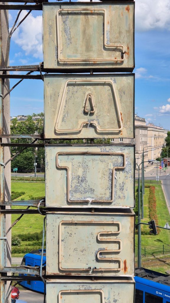 Stary, zabytkowy neon, widać pionowe prostopadłościenne elementy z neonowymi rurkami układającymi się w napis "LATE".